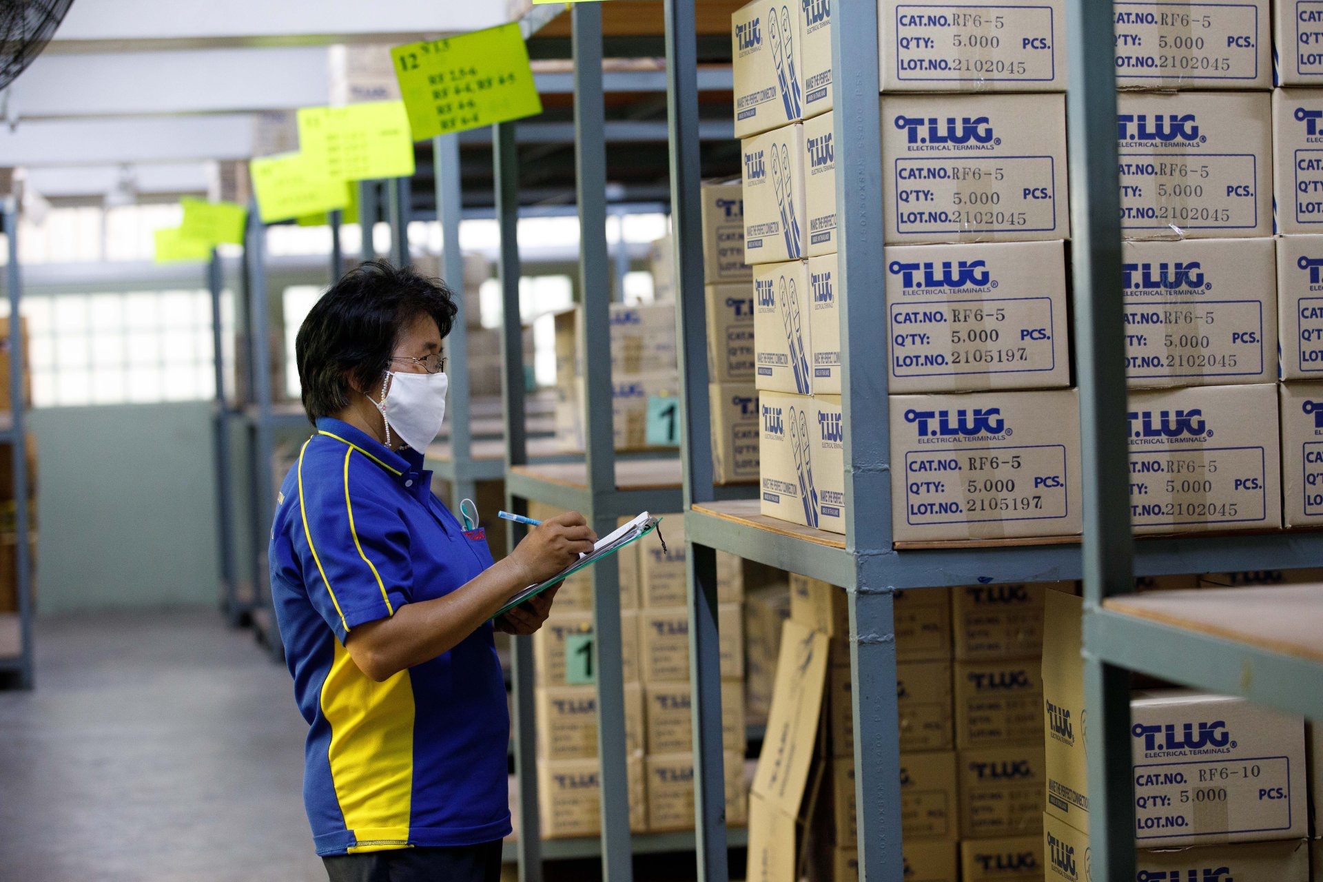 พนักงานตรวจนับกล่องหางปลา T.LUG ที่ติดรหัสรุ่นและเลขล็อตในคลังสินค้า